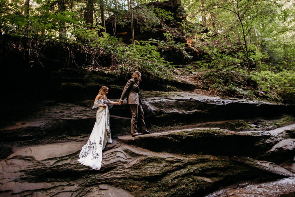 A man and a woman climb the rocks at their Turkey Run Wedding at Turkey Run State Park in Indiana